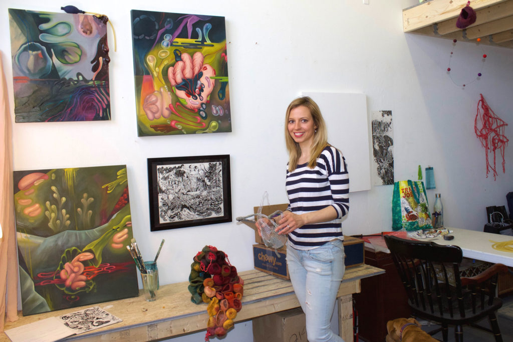 The artist stands in her art studio